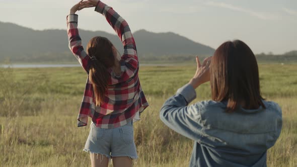 Teenage females take pictures on the smartphone while sunset.