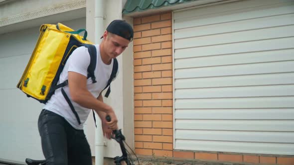 Young Fast Delivery Boy Riding Bike Walking to Gate Ringing in Door Bell alt