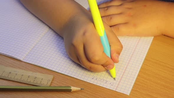 A Closeup of the Student's Hands Solves Mathematical Examples in a Notebook alt