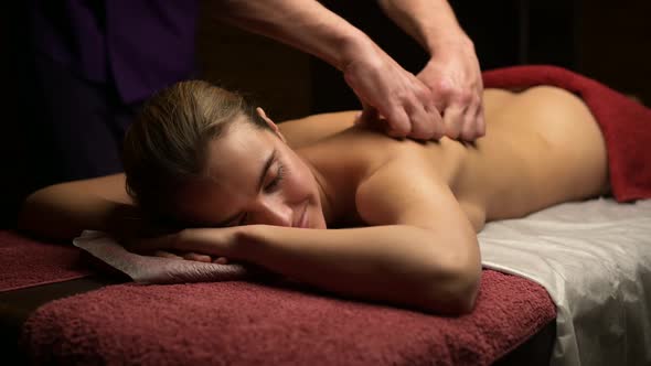 Young beautiful woman enjoying relaxing massage in the salon of masseur alt