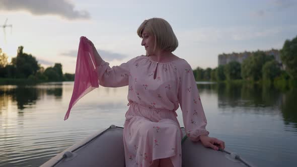 Happy Carefree Nonbinary Person Admiring Sunset on Lake Shaking Pink Kerchief in Hand alt