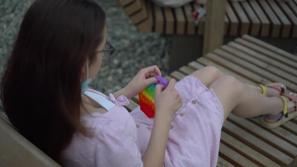 A Young Woman with Glasses Lies on a Deck Chair with a Popit in Her Hands alt