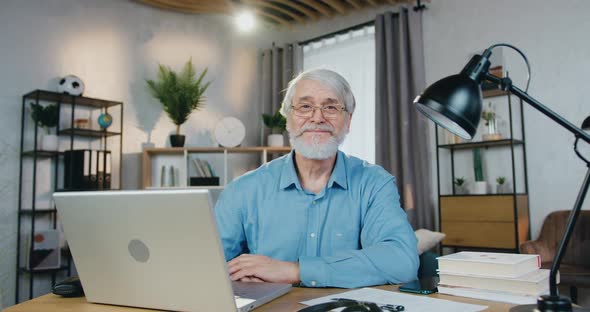 Smiling Aged Man Spending Leisure Time at Home with Laptop alt