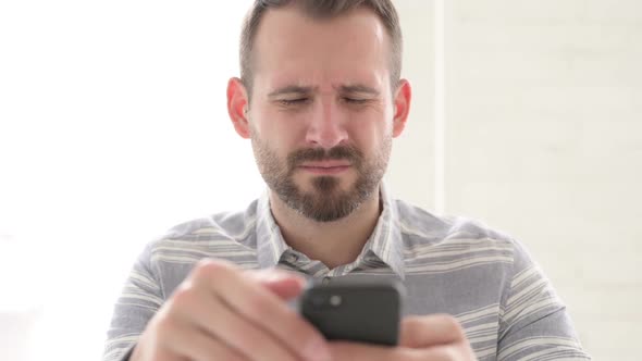Close Up of Man with Headache Using Smartphone alt