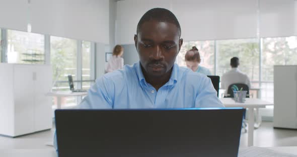 Medium Shot of Afroamerican Businessman in Formalwear Working on Laptop in Office alt