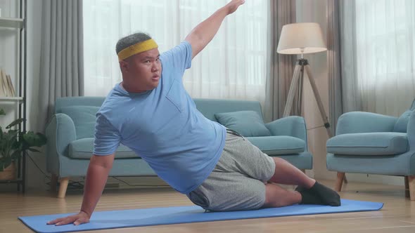 Fat Asian Man Doing Yoga In Side Plank Pose On Mat At Home alt