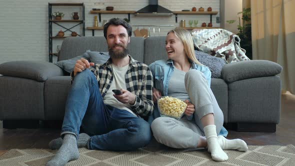 Laughing young couple laughing and watching comedy at the TV