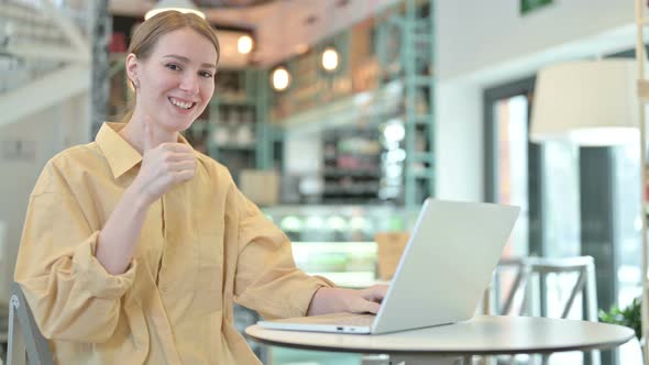 Thumbs Up By Young Woman Using Laptop in Cafe  alt