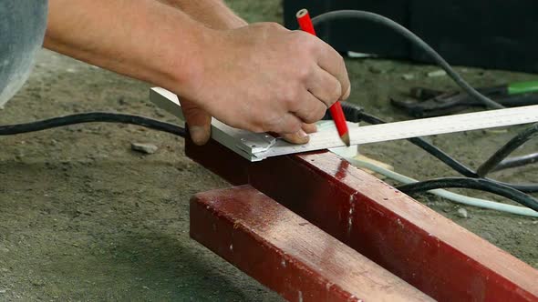 A Worker Makes Markings on a Metal Bar