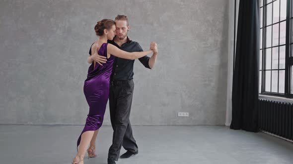 Camera Slowly Moving to a Pair Sensually Dancing a Tango in a Grey Studio