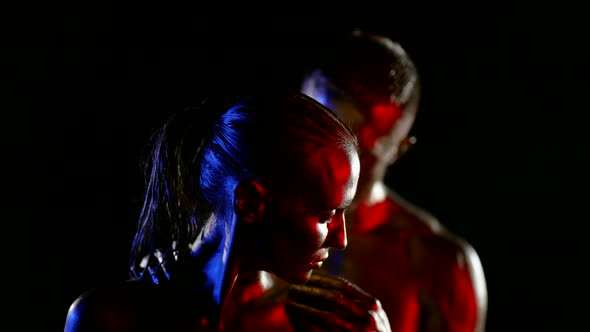 Portrait of a Couple with Golden Metallic Skin on a Black Background alt