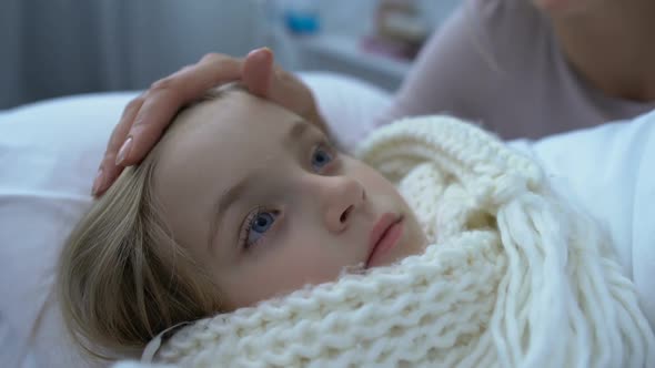 Mother Comforting Little Weak Daughter in Scarf Lying in Bed, Grippe and Health