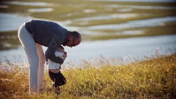 Young Father with His Baby Daughter on the Field - Teaching His Daughter How To Walk alt