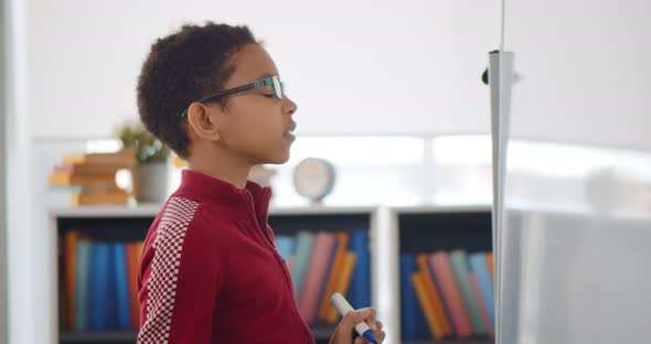 Portrait of African Boy Writing Solution of Sums on White Board at School alt