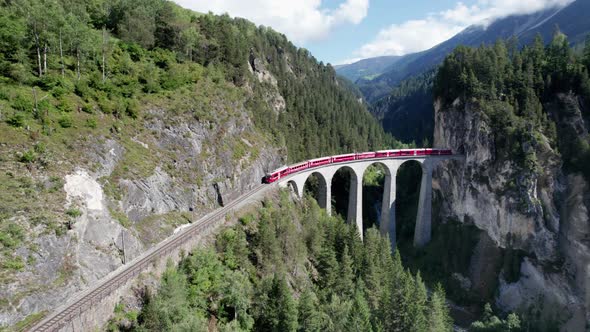 Aerial View of a Moving Red Train Along the Landwasser Viaduct in Swiss Alps alt