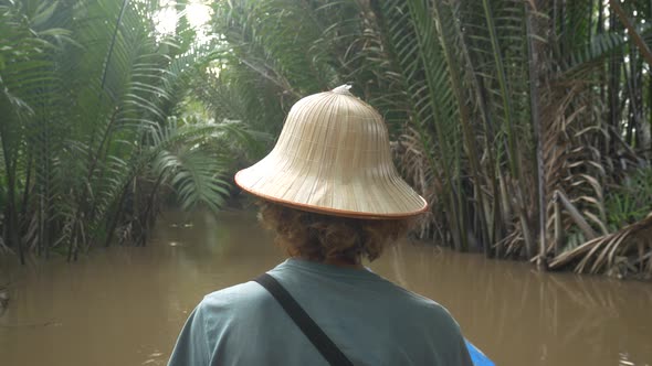 Boat tour in the Mekong River Delta region, Ben Tre, South Vietnam. Tourist with vietnamese hat on c alt