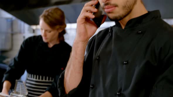 Chef looking at clipboard while talking on mobile phone 4k alt