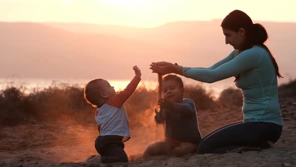 Slow Motion of Young Mom Playing with Kids with Sand at Sunset