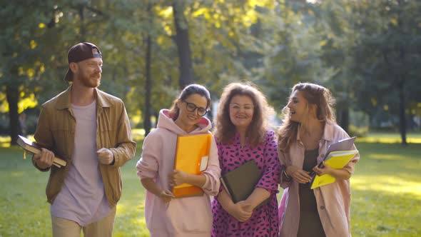 Group of Students Walking Together in Park and Communicating alt