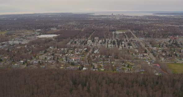 Helicopter aerial moving slowly from elevated beachside homes on rocky cliff, to pier, sunny day
