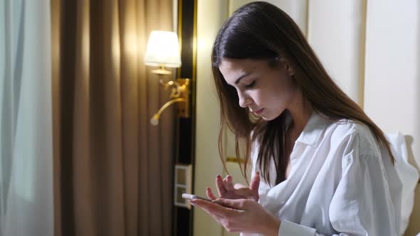 Young Attractive Woman Using Cellphone Browsing Online Website Shopping Before Sleep Sitting on Bed alt