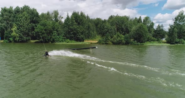 Wakeboarding in a Lake Near the Forest, Adult Man Surfs on the Water, Ride on a Wakeboarding Board alt