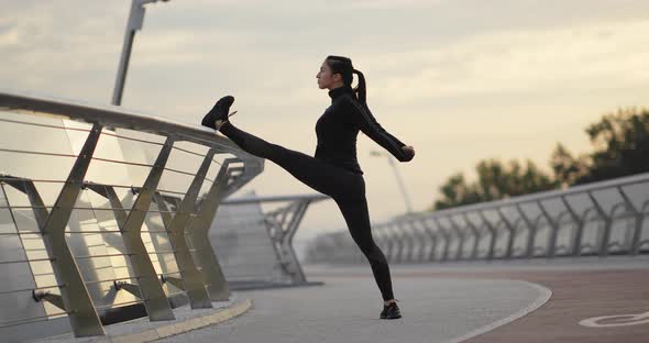 Sportswoman Warming Up Near Railing on Embankment