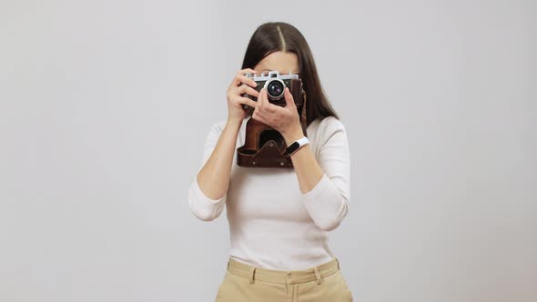 Joyful Woman In Beige Outfit Pulling A Focus And Making A Shot On Her Vitage Film Photocamera