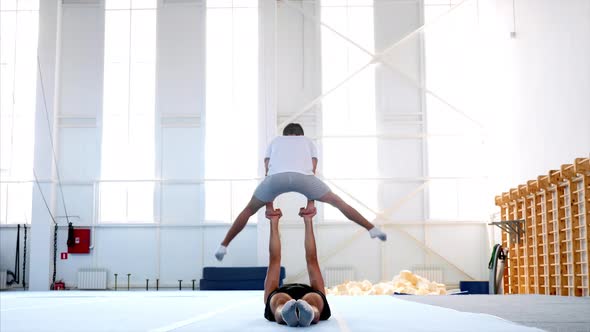 Two Acrobats are Practicing Acrobatic Handstand in Gym
