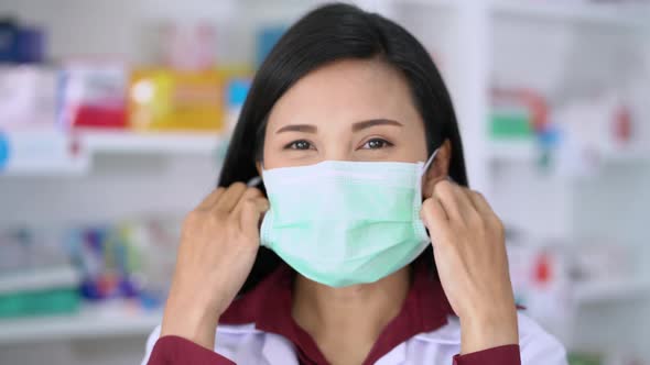 Portrait of woman pharmacist putting on medical protective face mask