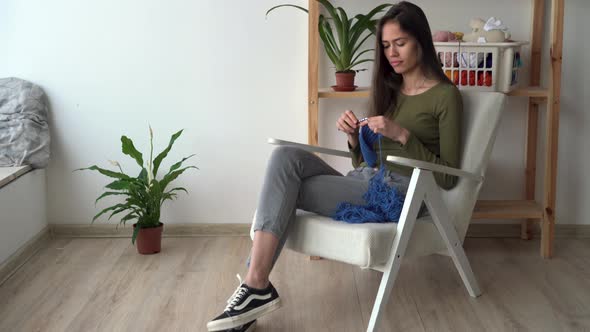 Needlework Concept Crochet Lesson Latino Woman Knit Scarf Sitting at Home in Armchair Hobby Leisure alt