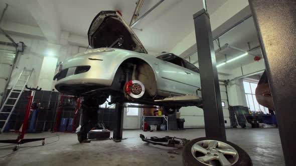 The car goes down on the lift in the auto repair shop alt
