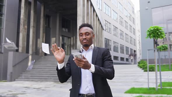 African American which Scattering Money in Front of Modern City Building Simultaneously Dancing alt