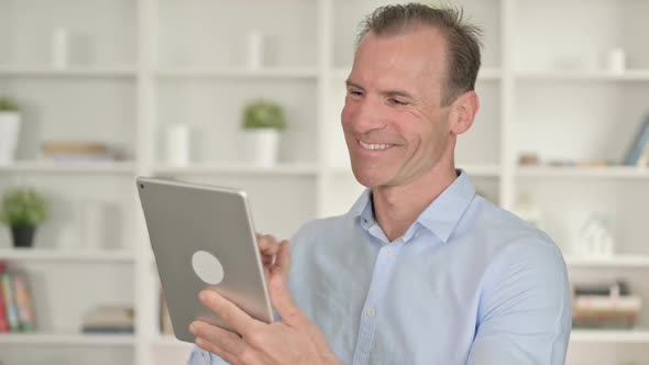 Portrait of Middle Aged Businessman Doing Video Chat on Tablet alt