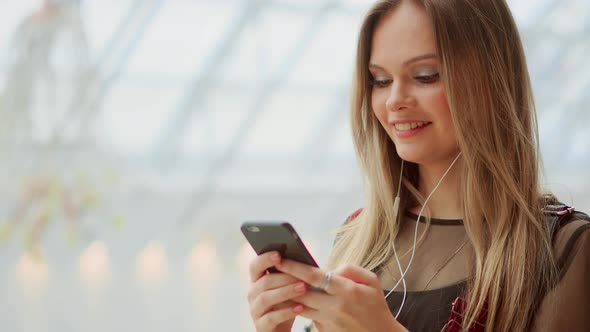 Girl Close-up with a Mobile Phone Writing a Text Message. Watch the Screen of a Smartphone alt
