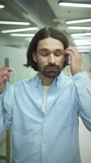 A Young Man is Putting Off a Protective Mask alt
