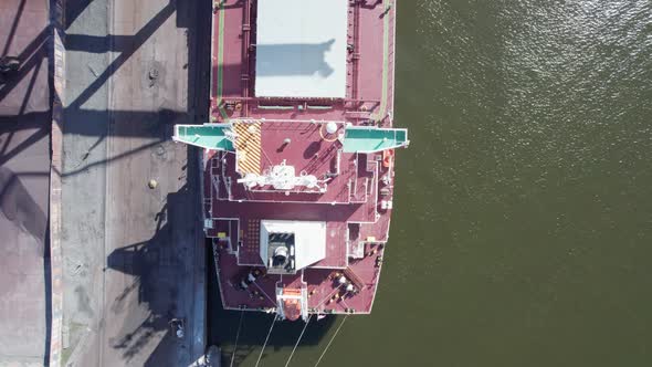 Aerial view of a cargo ship being unloaded by huge cranes in a port.