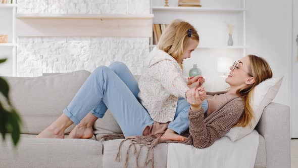 Happy Mother Woman Babysitter with Little Cute Girl Daughter Lie on Couch Relax Rest at Weekend alt