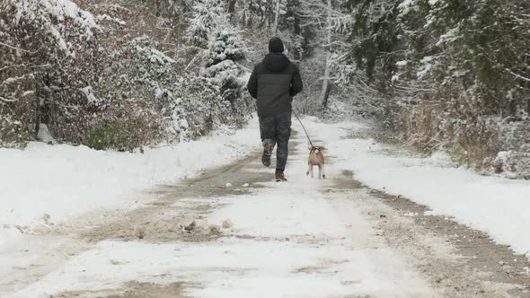 Man Runs with a Dog in Winter Into Forest
