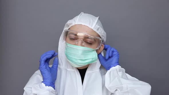 Doctor in Protective Costume Puts on a Mask