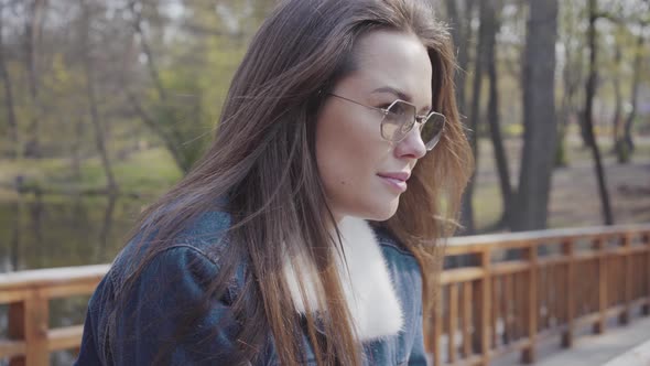 Portrait of Young Glamour Woman in Jeans Jacket Standing on the Wooden Bridge Looking Around and in alt