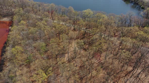 An aerial view of a orange colored lake during the day. The drone, while tilted down, pan left tilts alt
