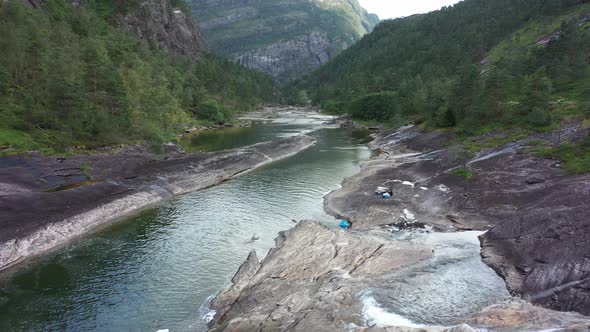 Family relaxing on rock besides beautiful river Ekso in Norway - Clean and fresh mountain water in c alt