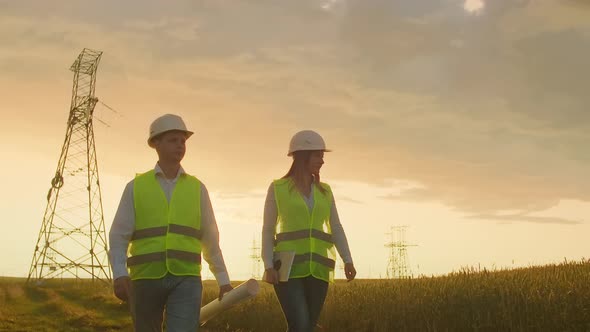 An Electrician Male and Female in the Fields Near the Power Transmission Line alt