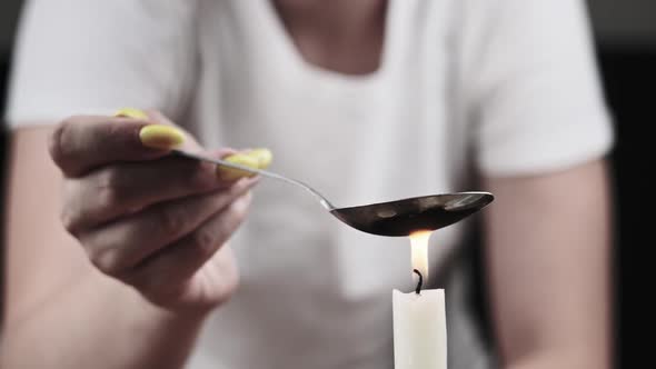 Young Woman Drug Addict Cooking Drugs in Spoon on Candle Flame alt