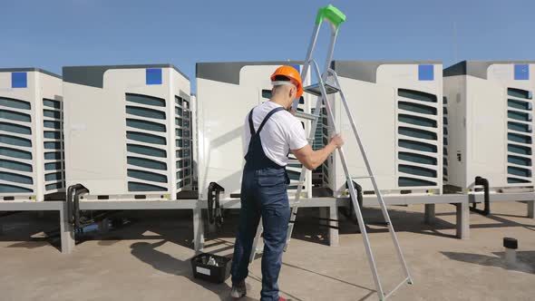The Young Engineer is Laying Out a Ladder and Climbing It Up alt