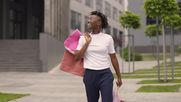 Young Happy Smiling Fashionable African American Woman Holding Paper Shopping Bags alt
