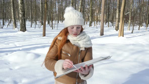 Red-Haired Teen Child Staying At Winter Park And Paints On Paper alt