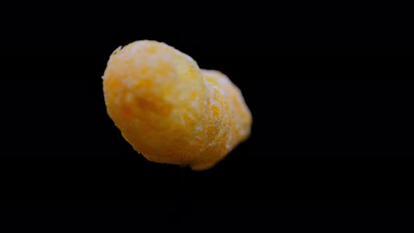 Cheesy Puff Snack Food Turning Slowly, Isolated On Black Background - close up alt