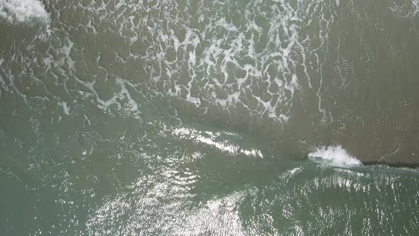 Overhead tilting shot waves crashing along shoreline alt